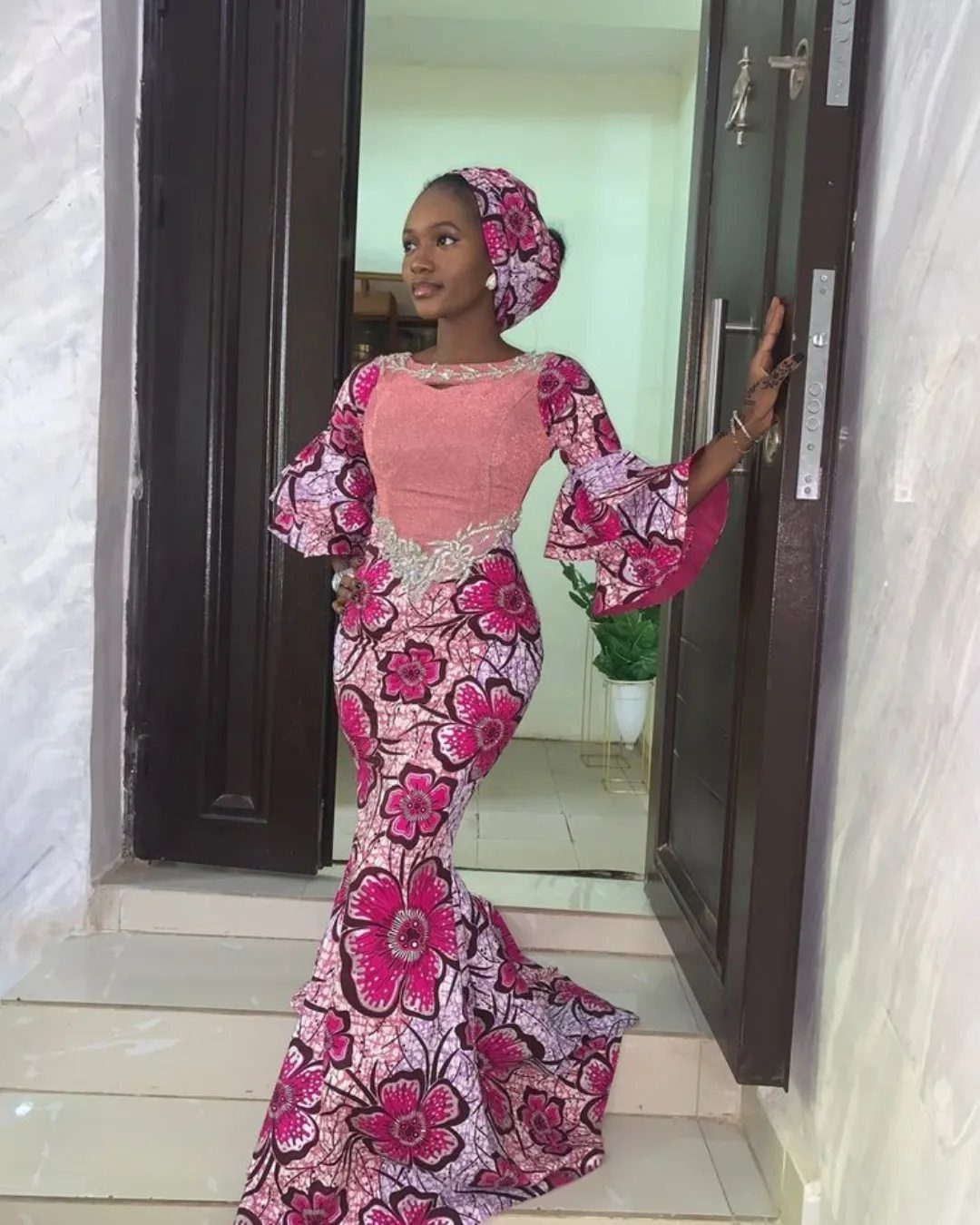 Woman in a pink and magenta floral print mermaid dress and matching headwrap.