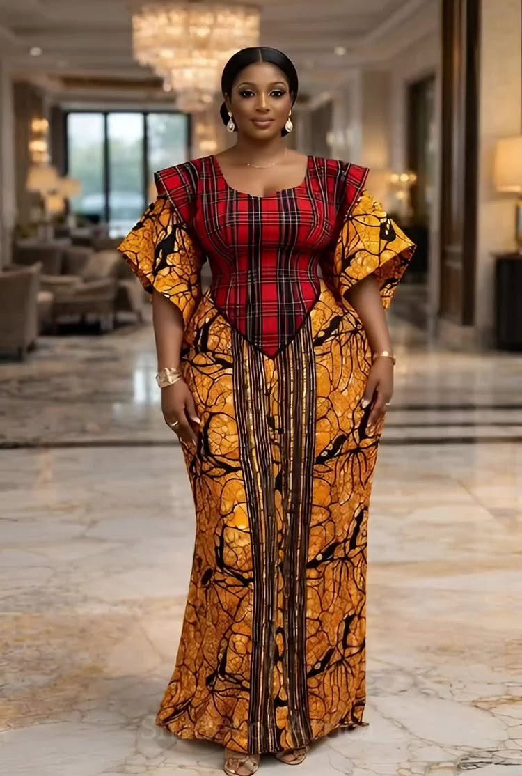 A woman posing in a vibrant red and yellow patterned Ankara gown.