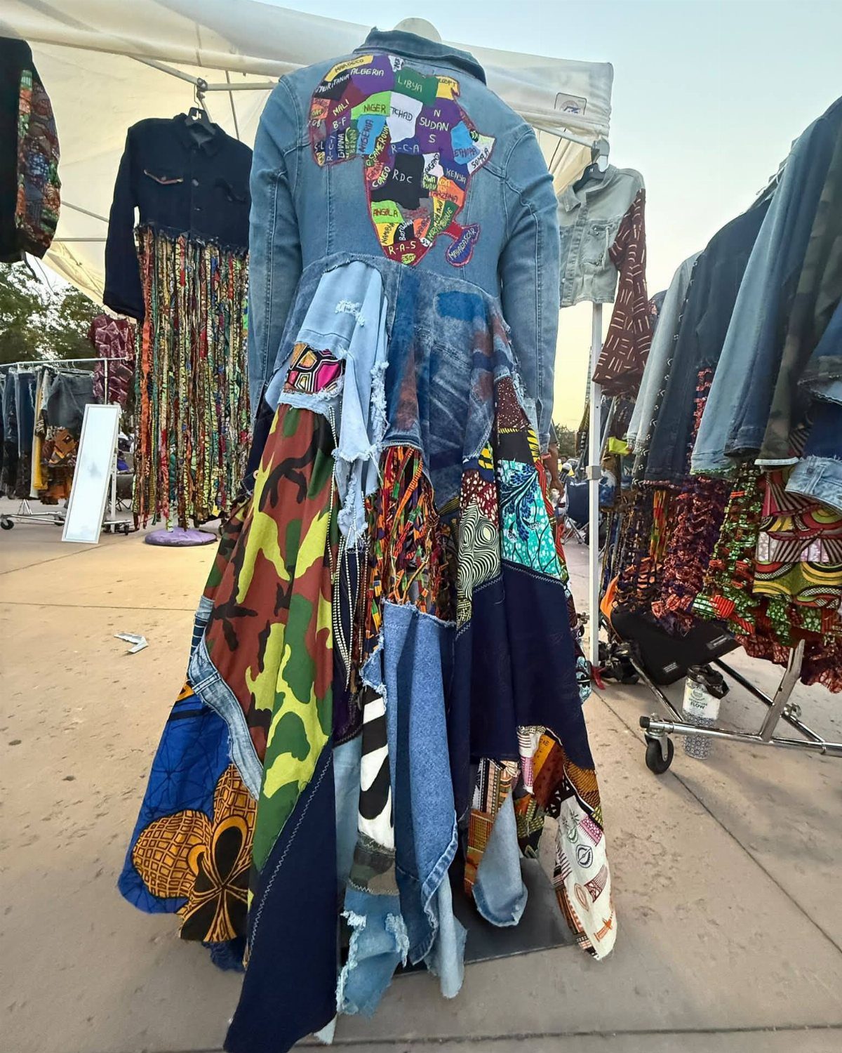 A denim jacket with a colorful patchwork skirt featuring African print fabric scraps on a mannequin.