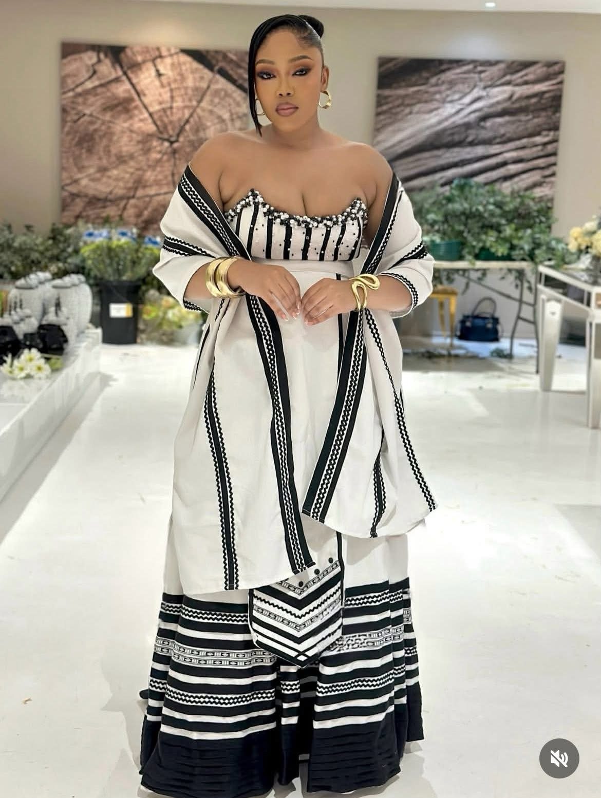 A woman wearing a white and black patterned off-the-shoulder dress and matching wrap.