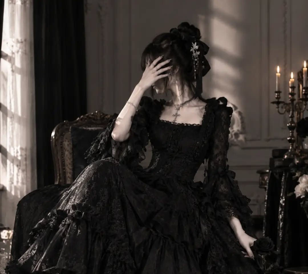 A woman wearing a dramatic black lace tiered ballgown sitting in an elegant room.