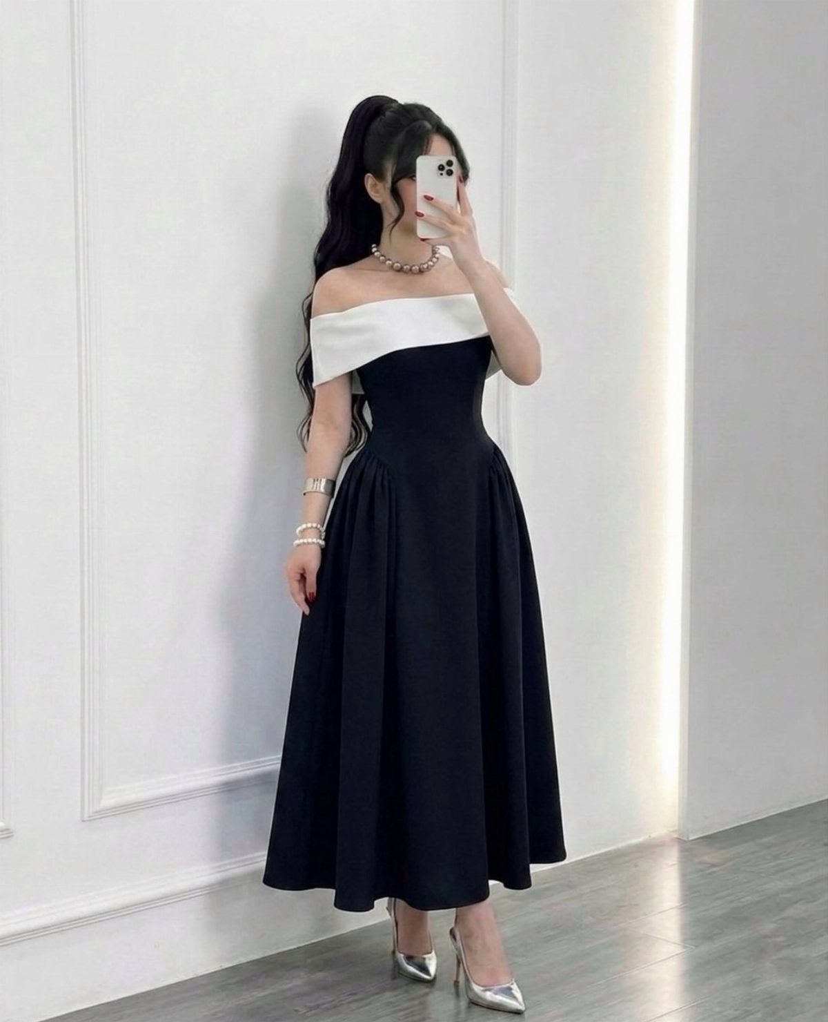 Woman in a black off-the-shoulder midi dress posing for a mirror selfie.