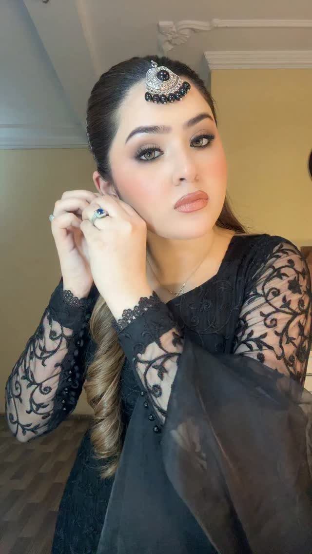 A woman wearing an elegant black lace dress and traditional silver head jewelry.