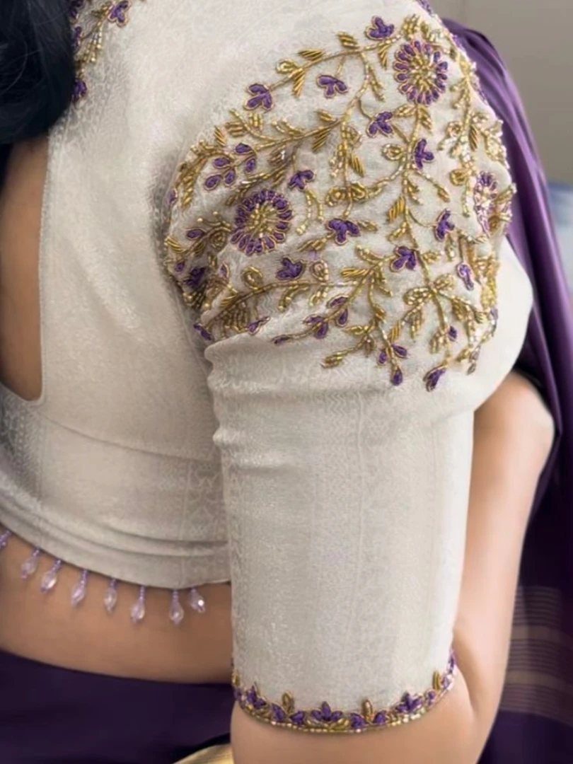 Cream blouse with heavy gold and purple floral beadwork on the puff sleeve and crystal droplets.