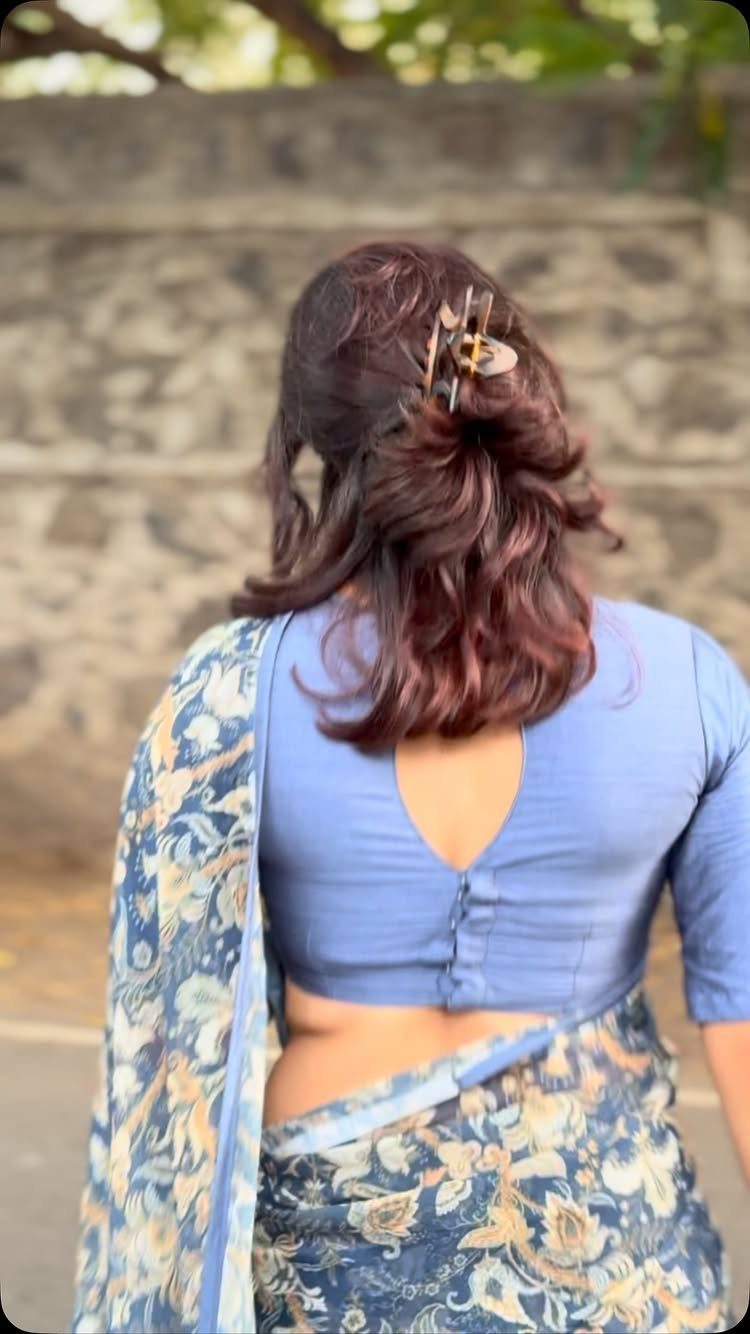 Woman from behind wearing a light blue blouse with a teardrop keyhole back and floral saree.