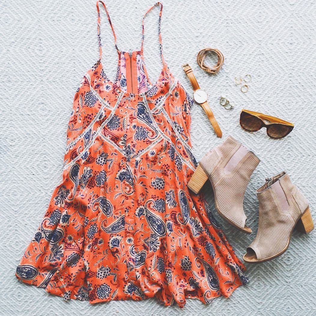 Orange paisley sundress paired with beige suede ankle boots and gold accessories on a light background.