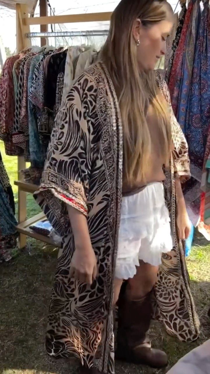 A woman wearing a patterned animal print kimono over white shorts and brown boots.