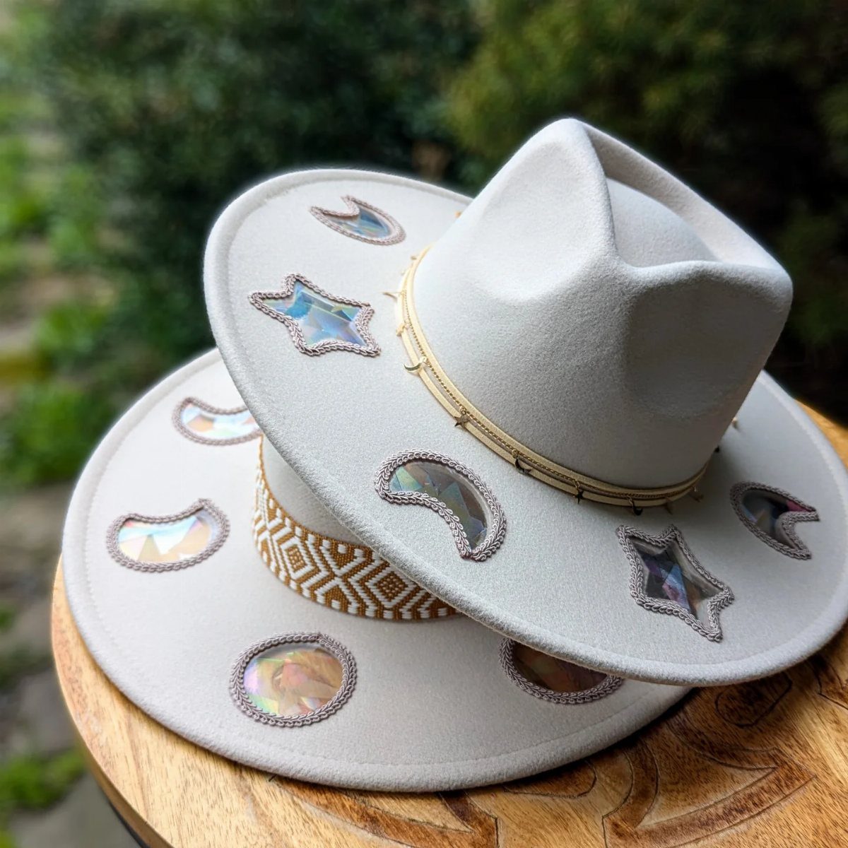 Two grey wide-brimmed felt hats with celestial star and moon decorations stacked on wood.