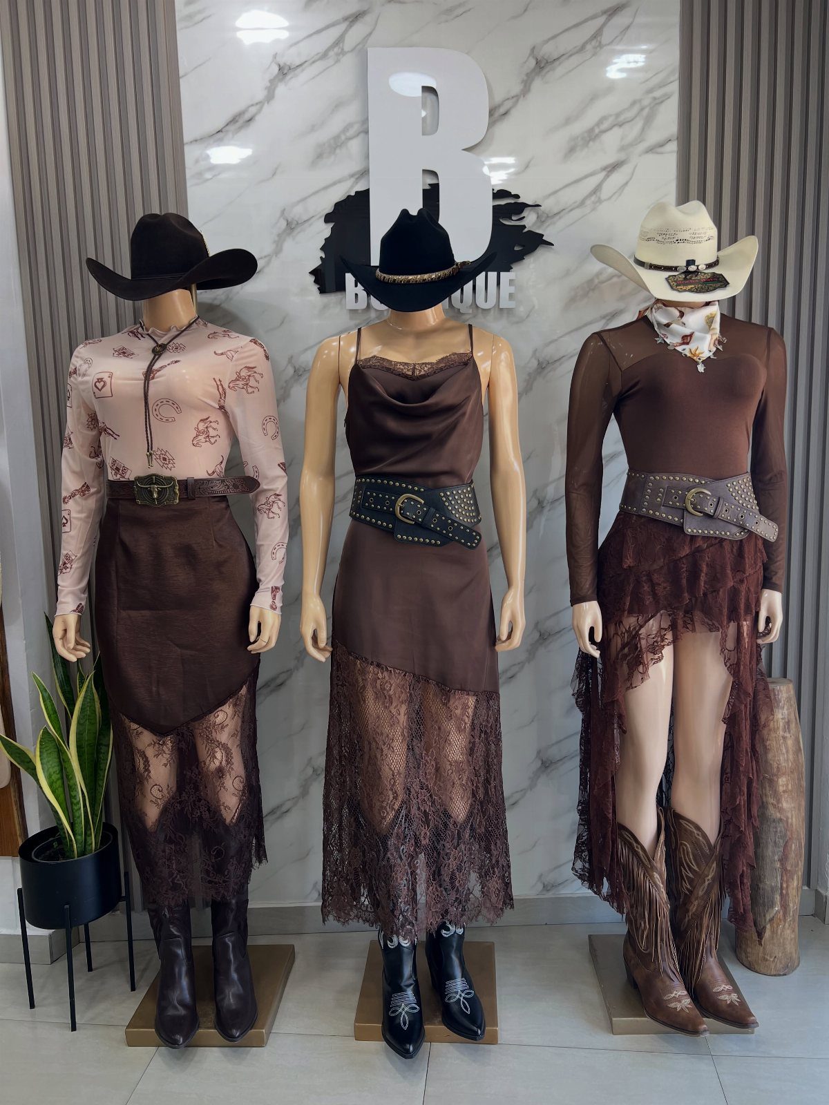 Three mannequins wearing bohemian Western outfits with cowboy hats, lace dresses, and boots.