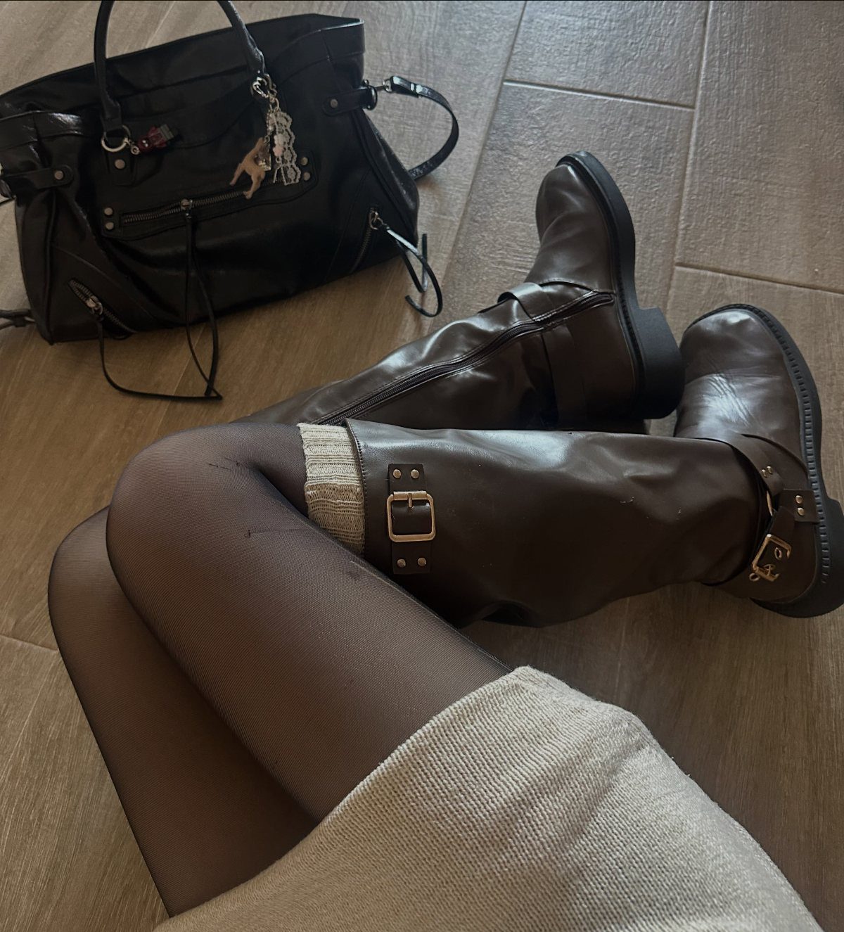 Brown leather boots with buckle details worn with dark tights and a beige skirt.