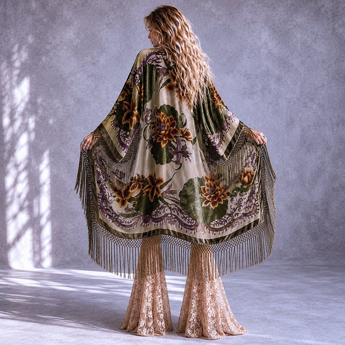 Woman wearing a floral patterned kimono with long fringe over lace wide-leg trousers.