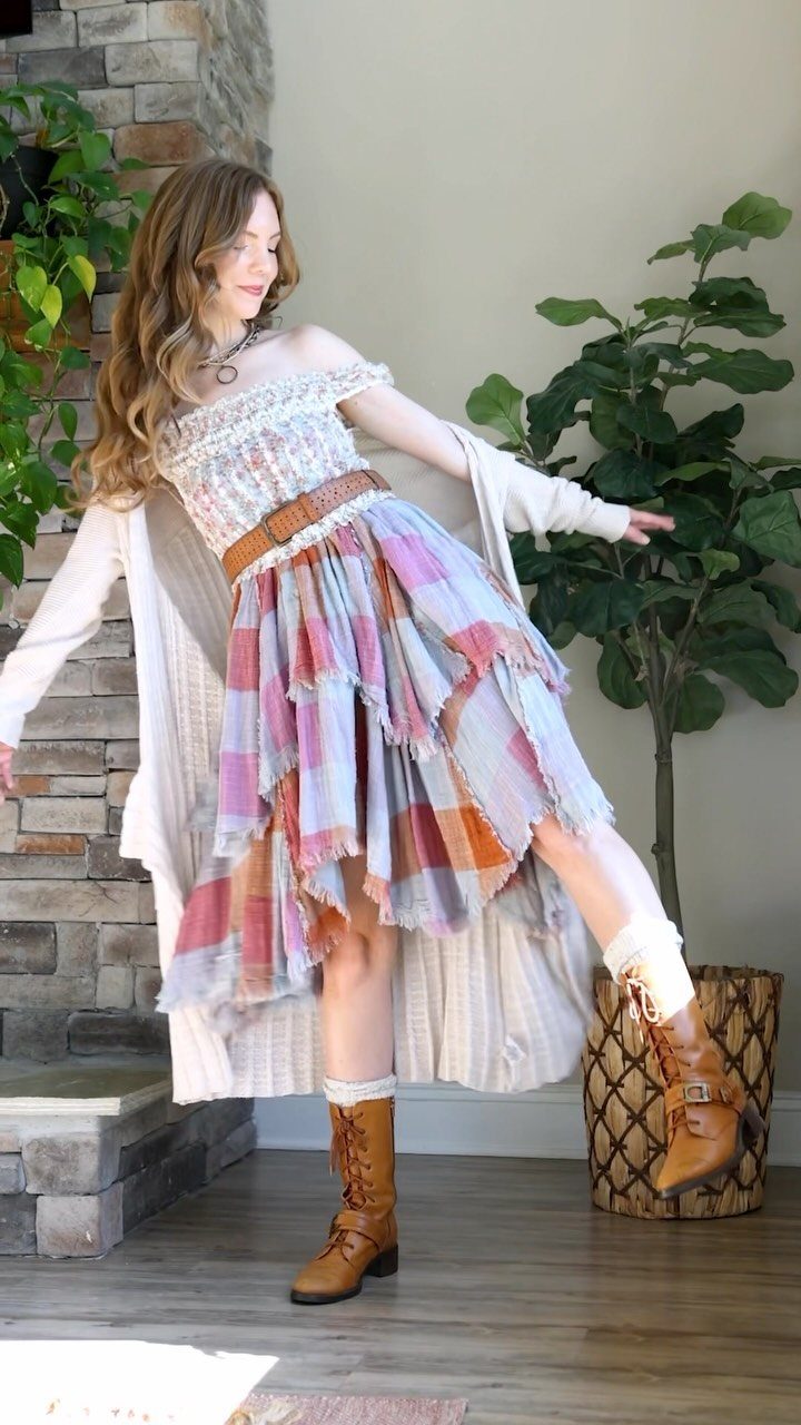 Woman posing in a layered boho outfit with a patterned skirt and long cardigan.