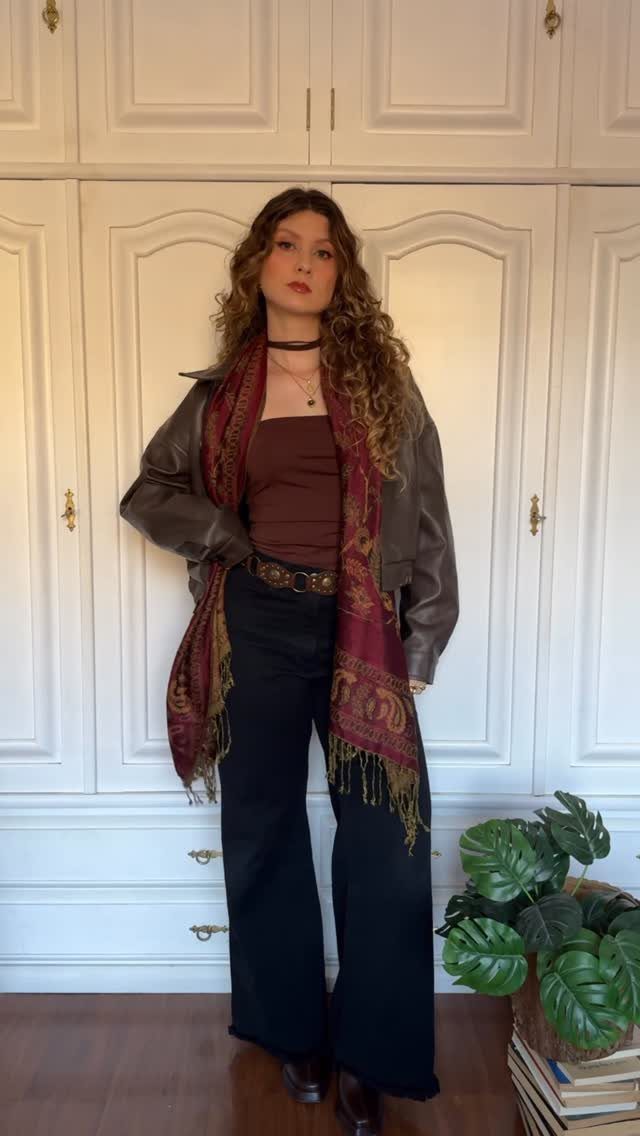 Woman wearing a burgundy paisley print scarf, leather jacket, and black wide-leg pants.