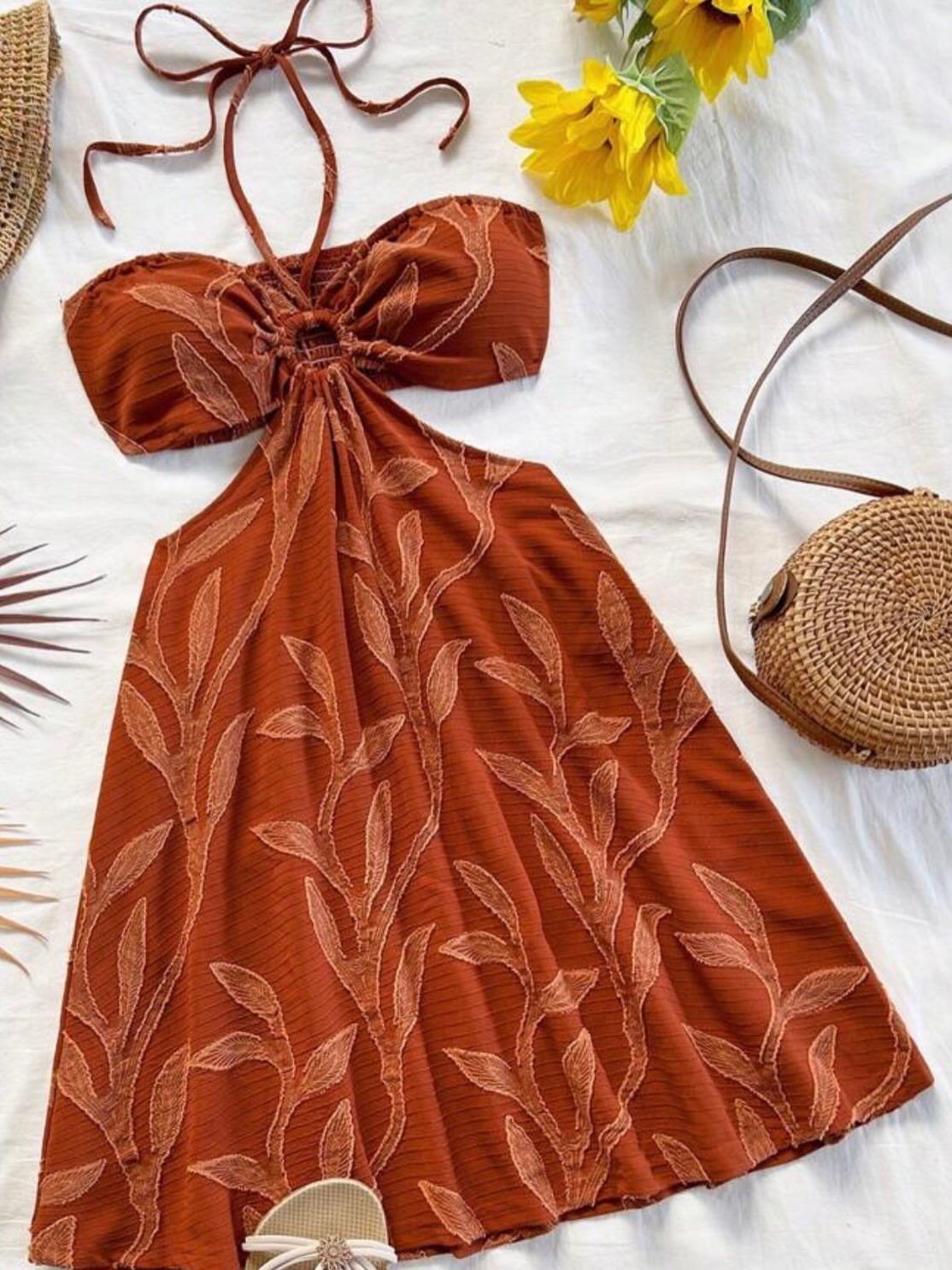 Rust-colored halter summer dress with a leaf pattern laid flat on a white background.