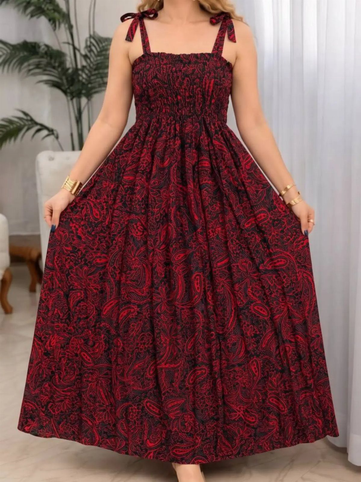 Woman wearing a red and black paisley print maxi dress with tie-straps.