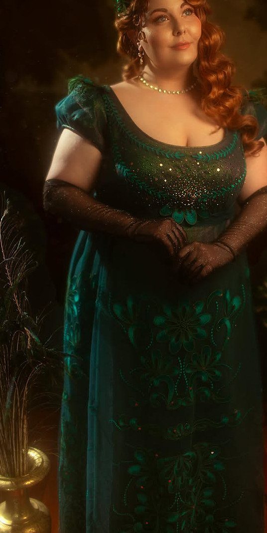 A woman with red hair wearing an emerald green Regency-style beaded gown and dark gloves.