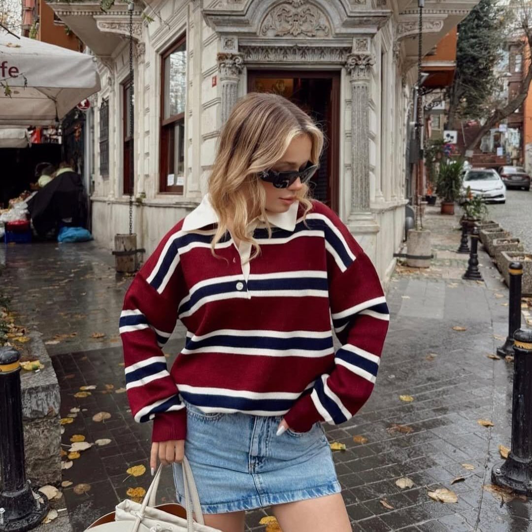 Woman wearing a striped burgundy rugby sweater and a denim mini skirt on a city street.