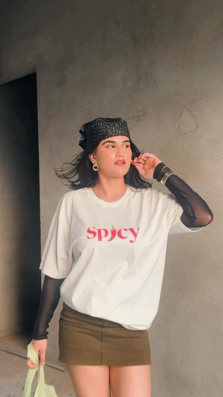 Woman wearing a white graphic t-shirt with red text and a black bandana.