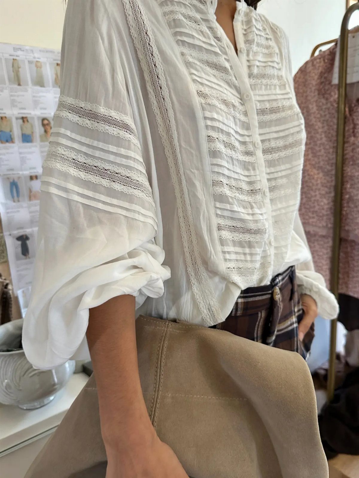 White textured blouse with lace details and voluminous sleeves worn by a woman.