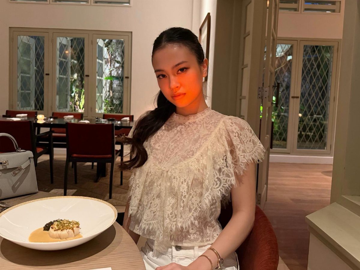 A woman wearing a white ruffled lace blouse sitting at a restaurant table.