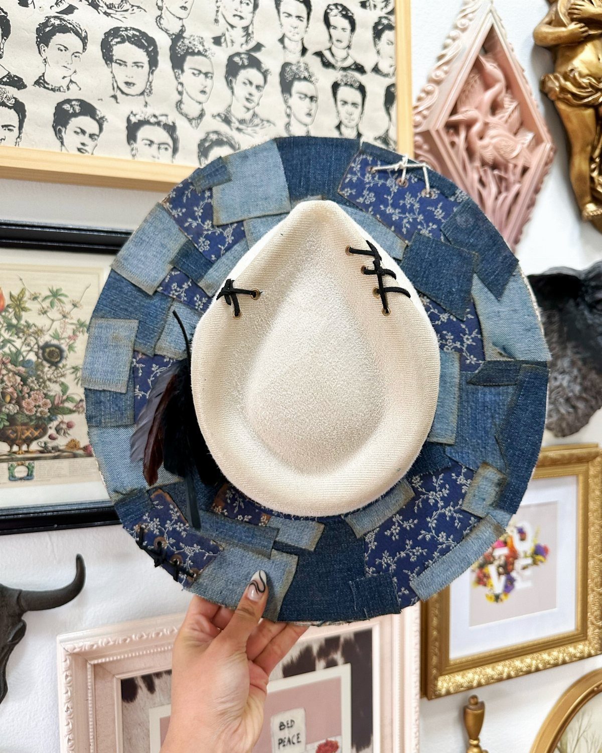 A patchwork denim cowgirl hat with a white crown held by a hand.