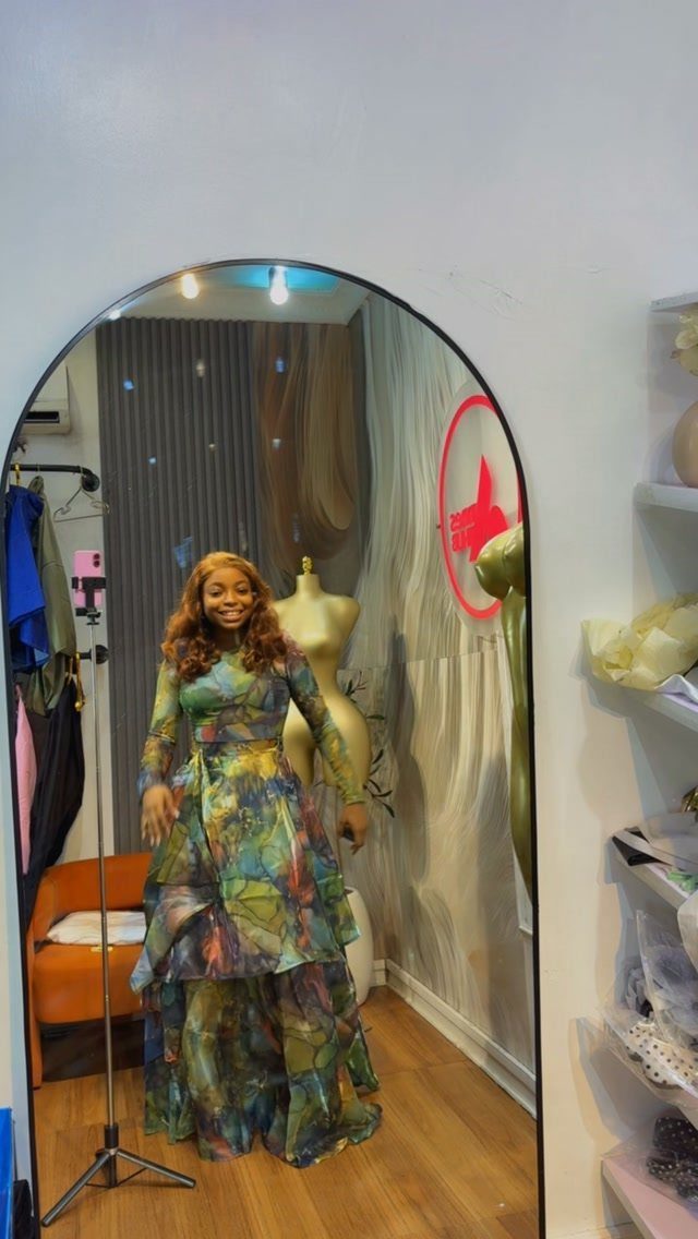 A woman posing in a colorful, patterned long-sleeved maxi dress in front of a mirror.