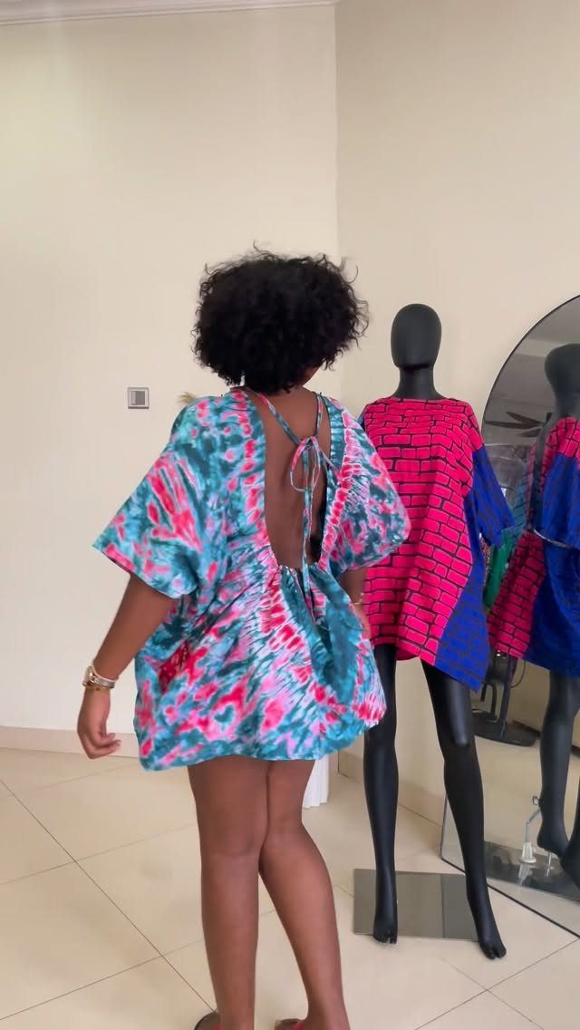 Woman wearing a colorful tie-dye dress with a dramatic open back design.