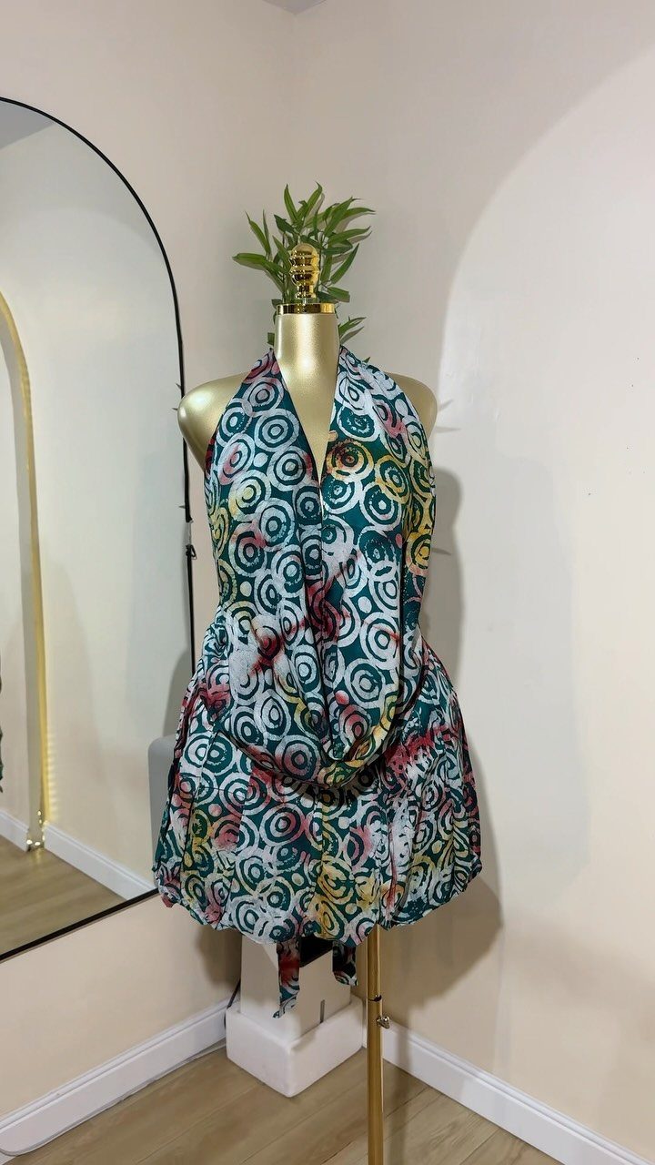 A patterned teal and white halter dress displayed on a mannequin in a room.