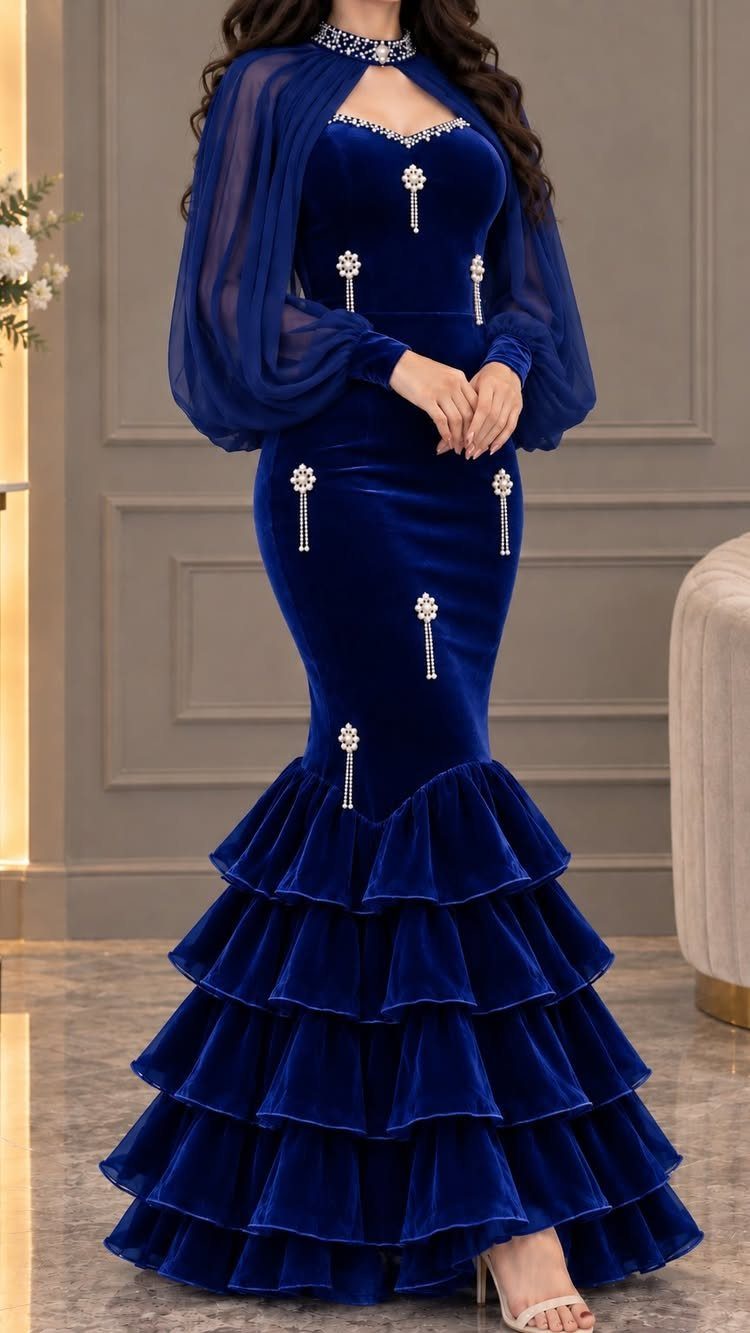 Woman wearing a royal blue velvet mermaid dress with sparkling details and tiered ruffles.