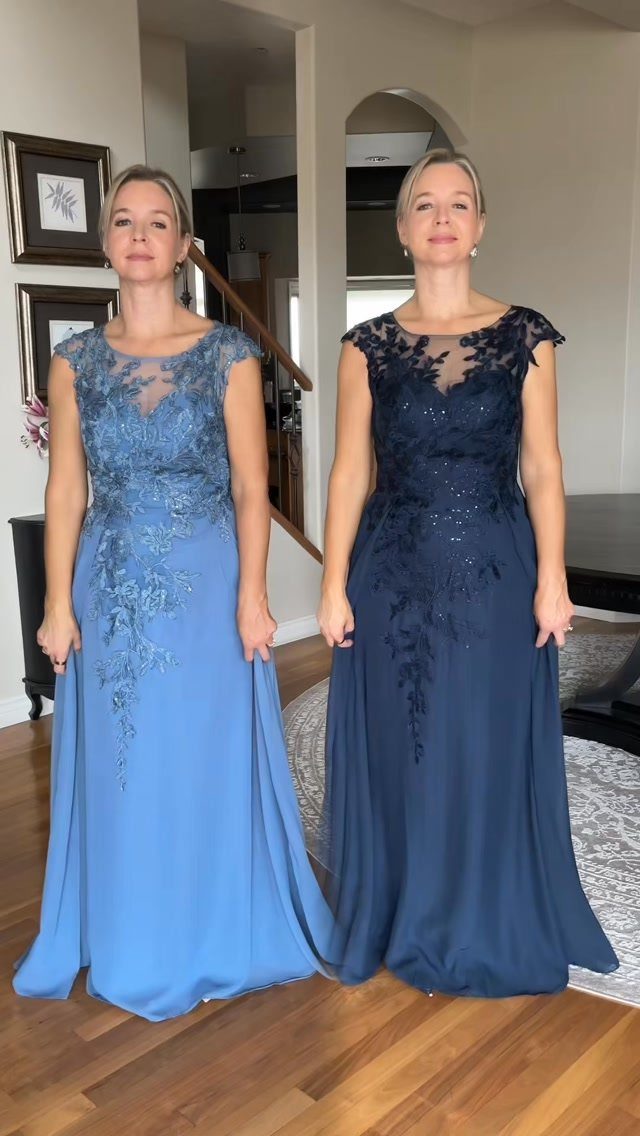 Two women posing in floor-length lace evening dresses in shades of light and dark blue.