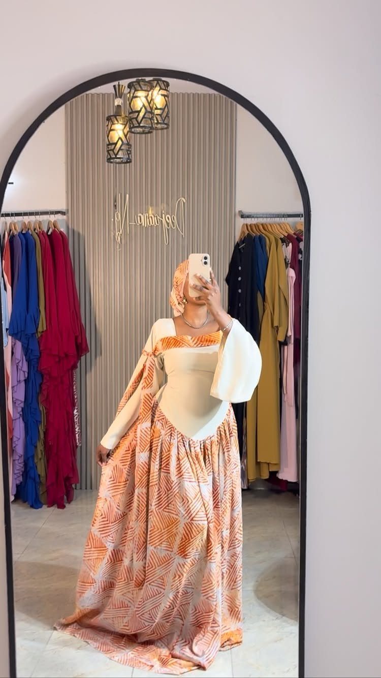 Woman posing in a long patterned maxi dress with a cream corset bodice.