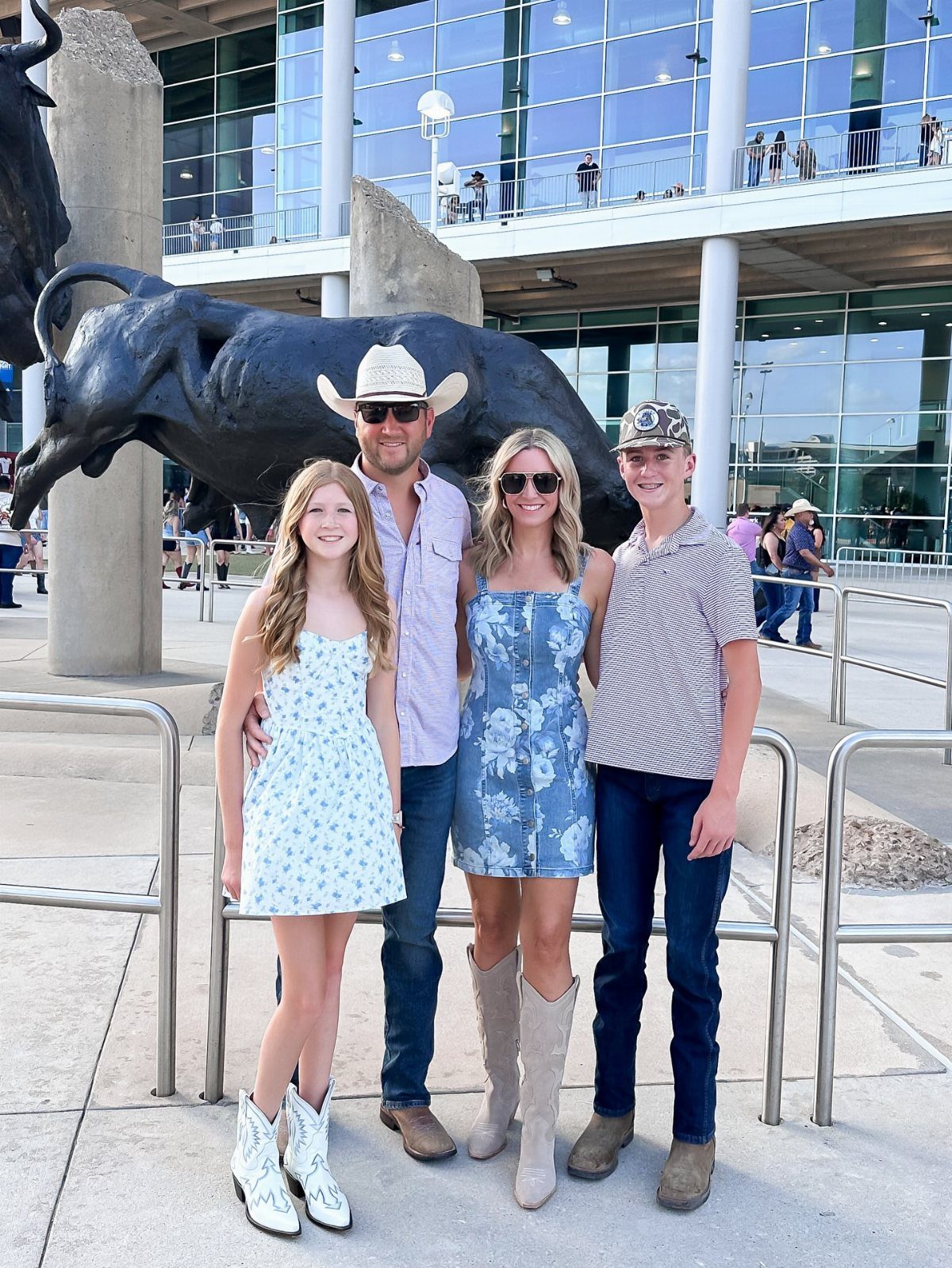 A family posing together outdoors wearing casual summer clothing and cowboy boots.