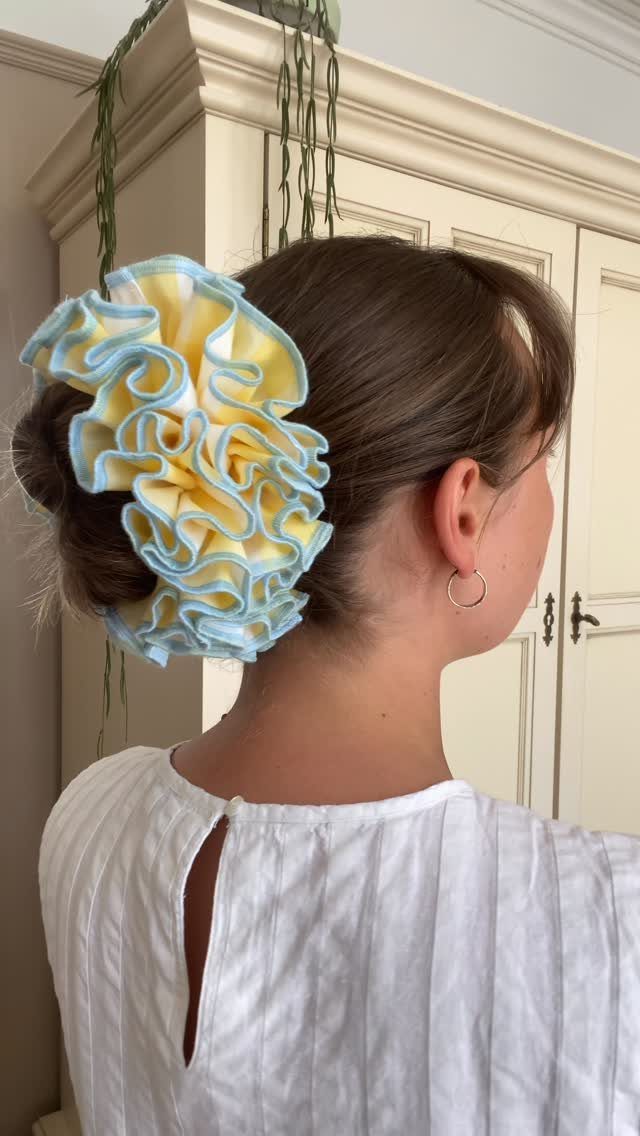 A woman with a large yellow and blue ruffled scrunchie in her hair.