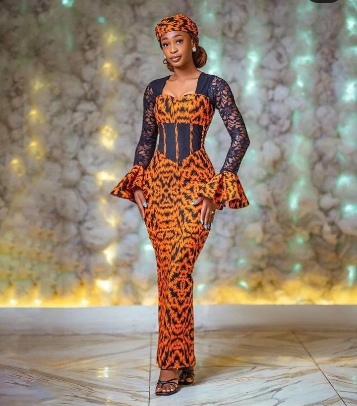 Woman wearing a long orange and black patterned dress with a structured corset-style bodice.
