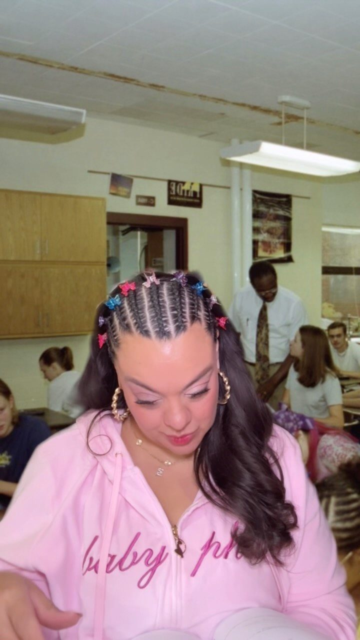 Woman with braided hair decorated with colorful butterfly clips and large hoop earrings.