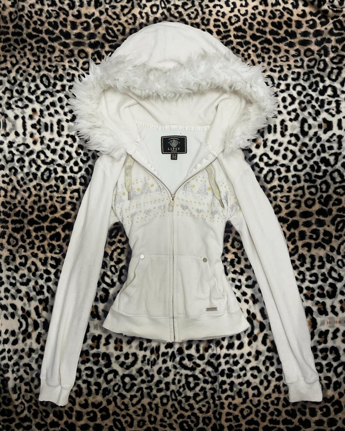 White zip-up hoodie with a large faux-fur trimmed hood on leopard print fabric.
