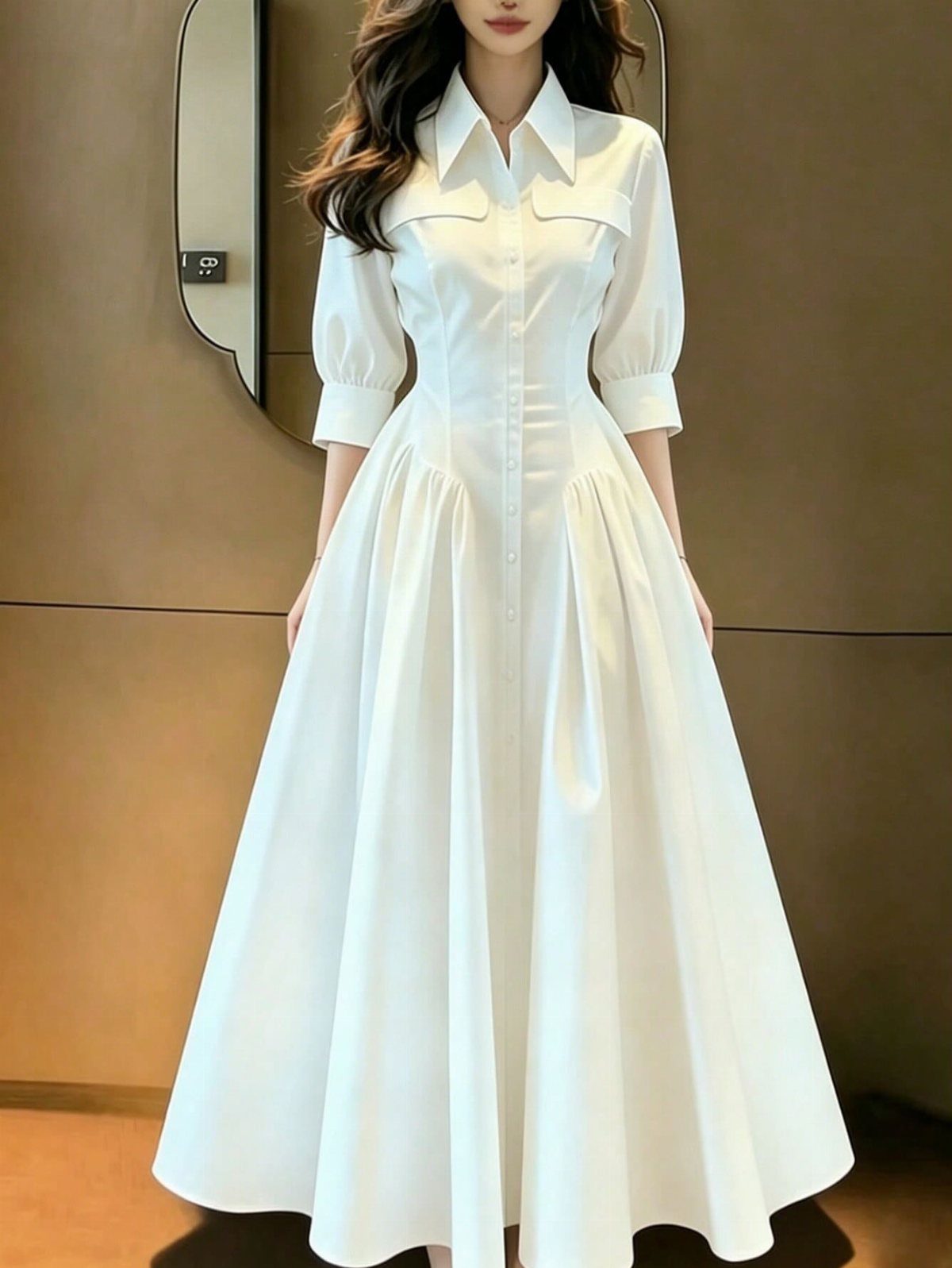 A woman wearing a long white A-line dress with a button-down front and puffed sleeves.