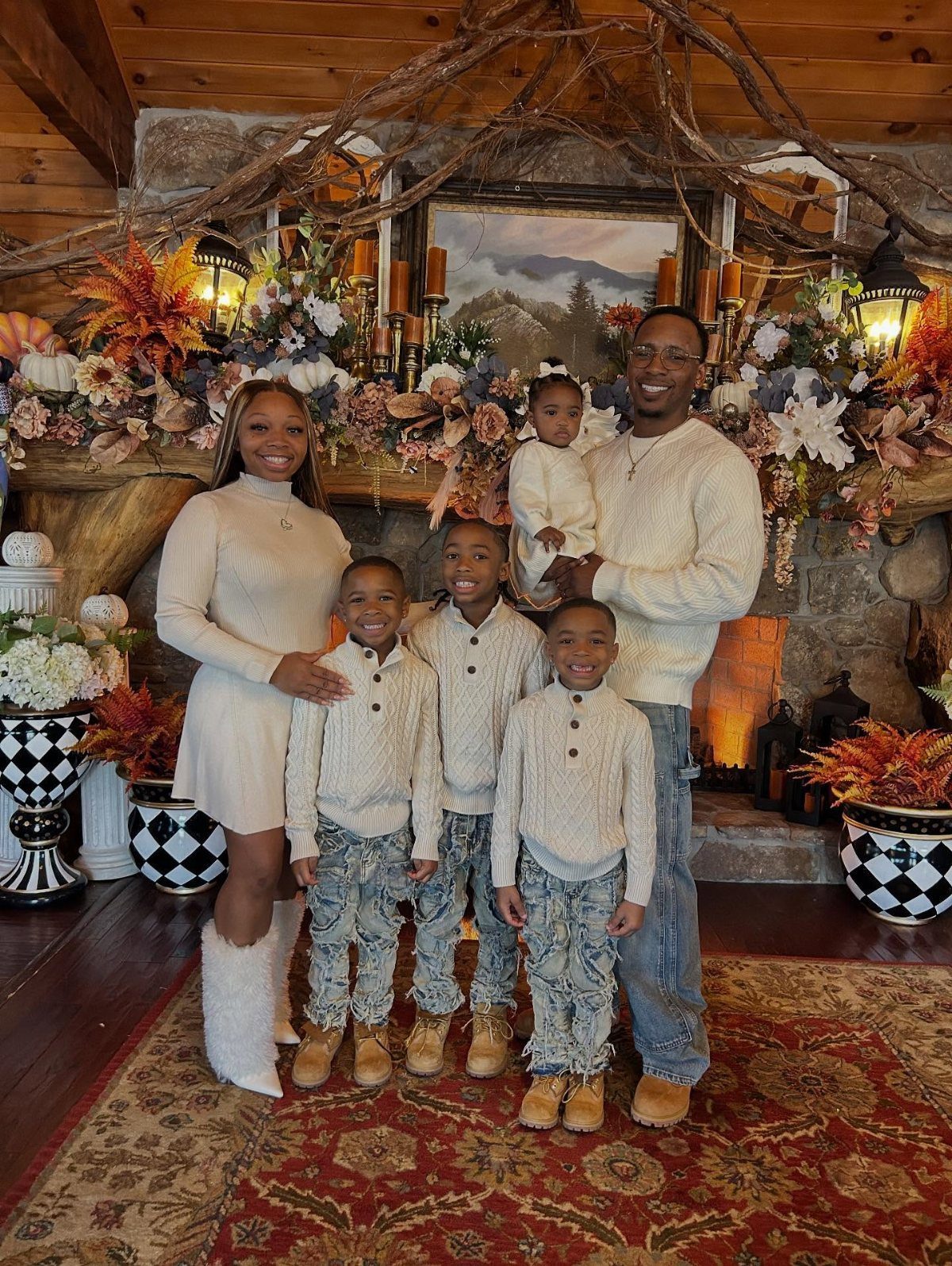 A smiling family of six wearing coordinated cream knit sweaters posing in a decorated room.