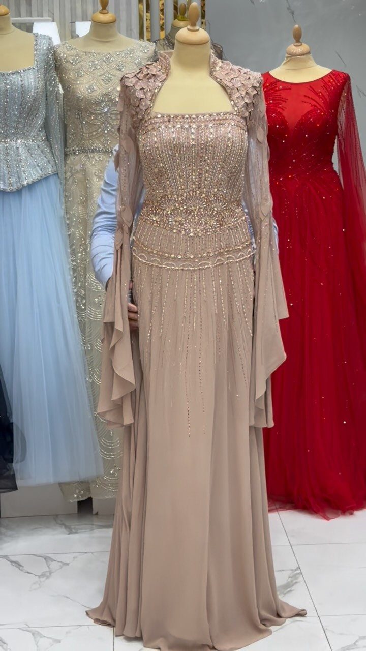 Beige embroidered evening gown on a mannequin surrounded by blue and red formal dresses.