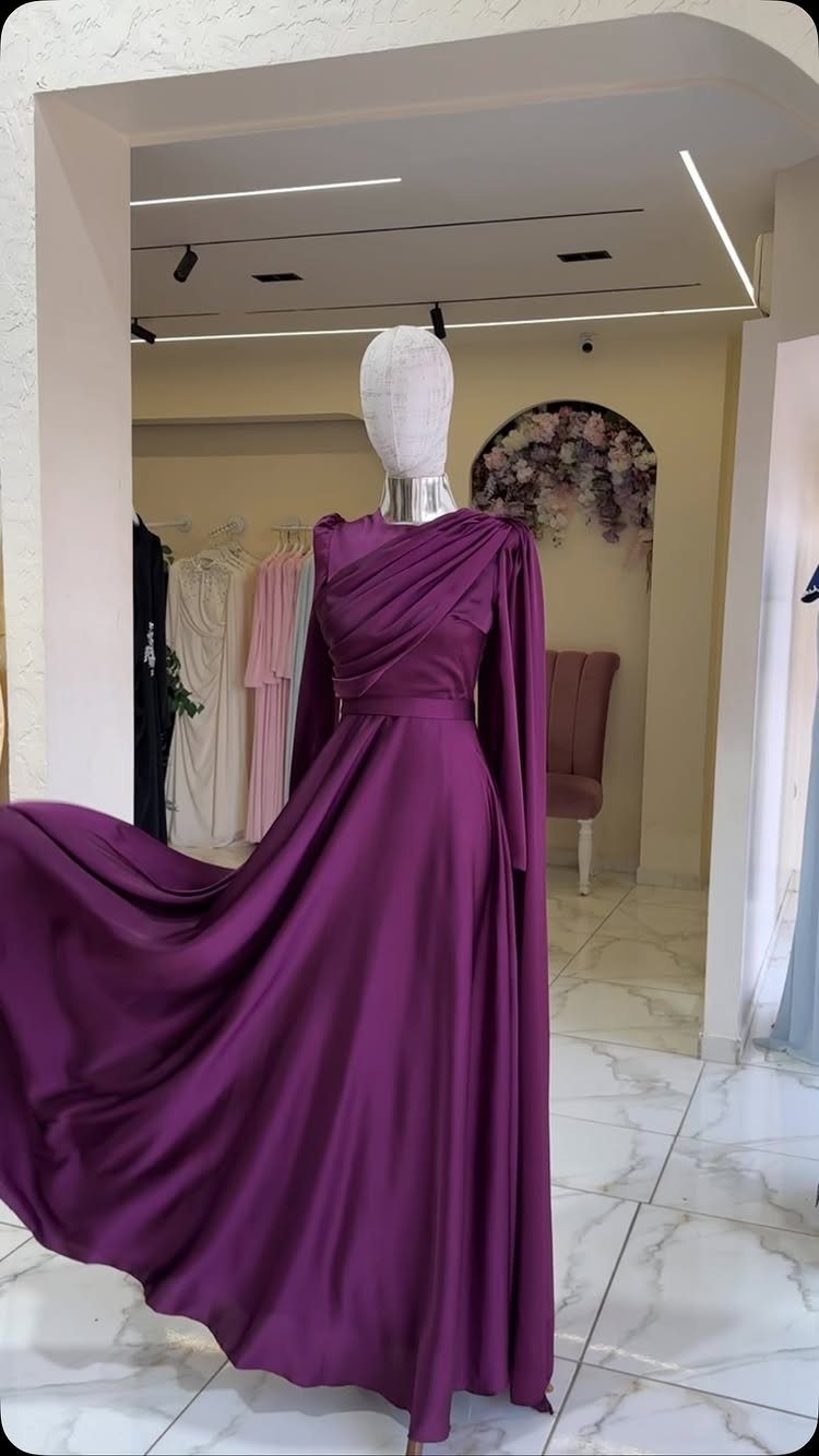 A purple satin evening gown displayed on a mannequin in a bright clothing boutique.
