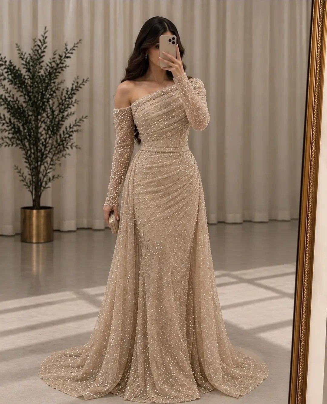 Woman in a shimmering champagne sequined formal gown taking a mirror selfie indoors.