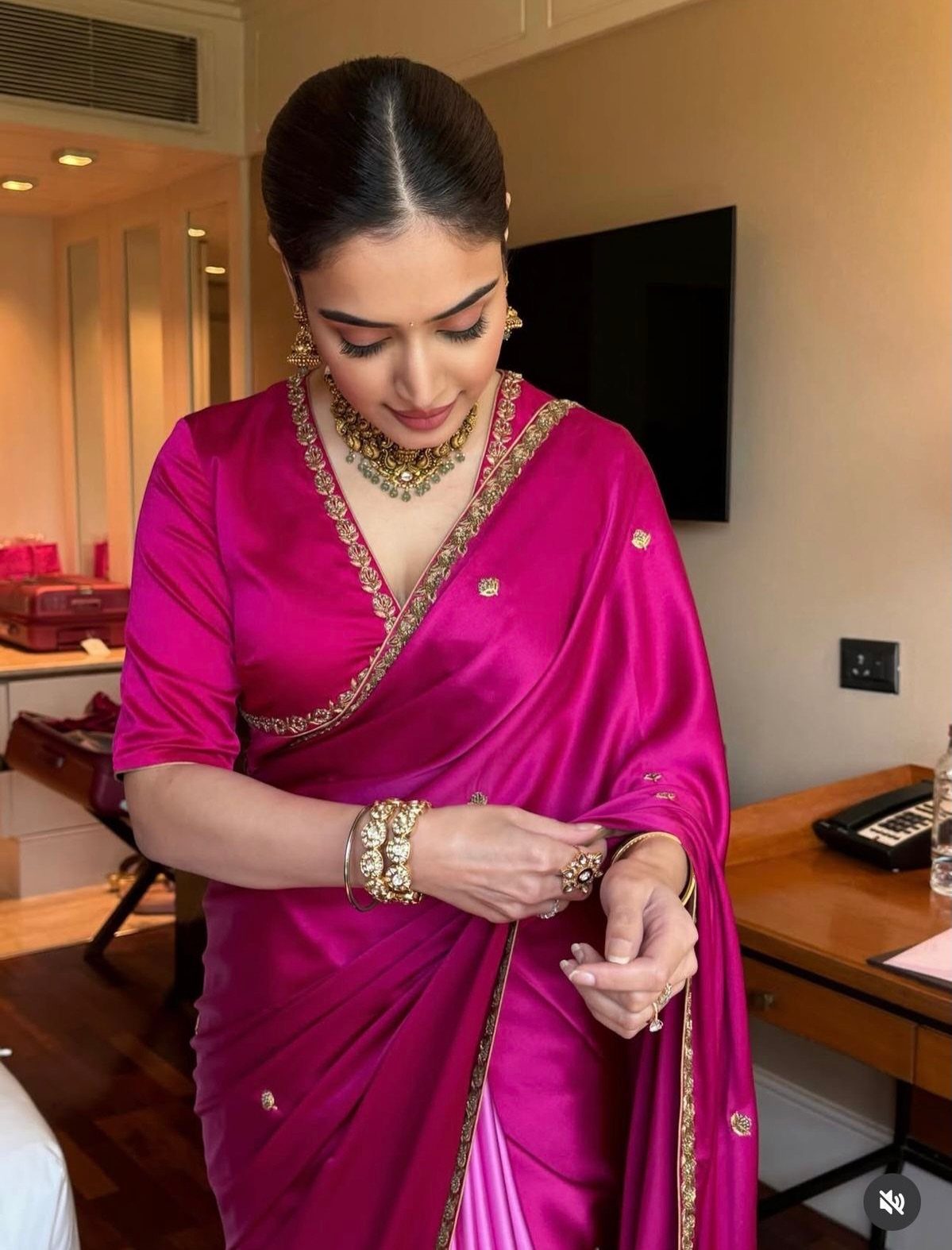 A woman dressed in a magenta silk saree with gold embroidery and traditional jewelry.