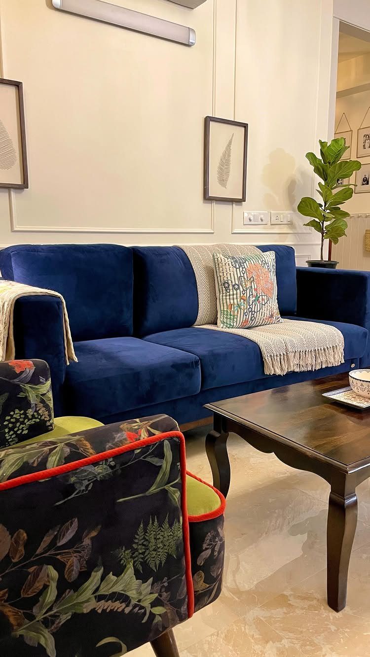 A navy blue velvet sofa with decorative pillows sits in a modern living room.