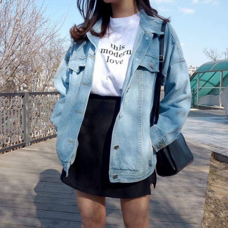 Person wearing a light blue denim jacket and a white graphic t-shirt with black text.