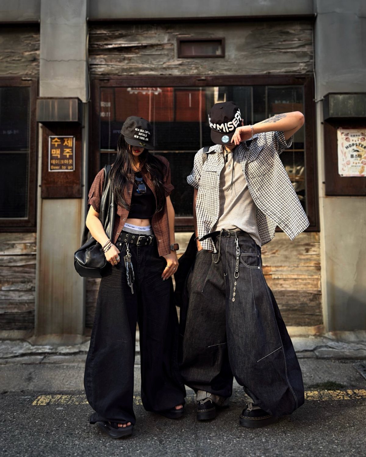 Two people posing in oversized streetwear including wide-leg trousers and baggy denim pants.