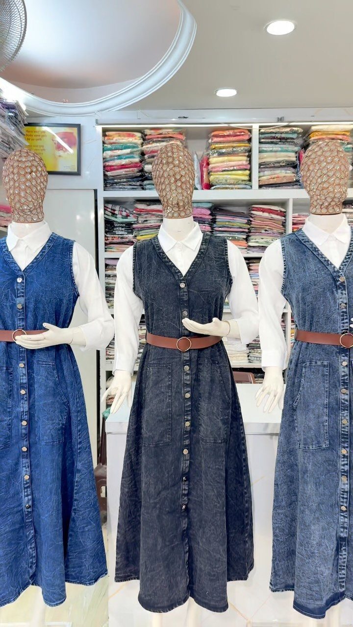 Three mannequins wearing denim dresses over white shirts with brown belts in a clothing store.