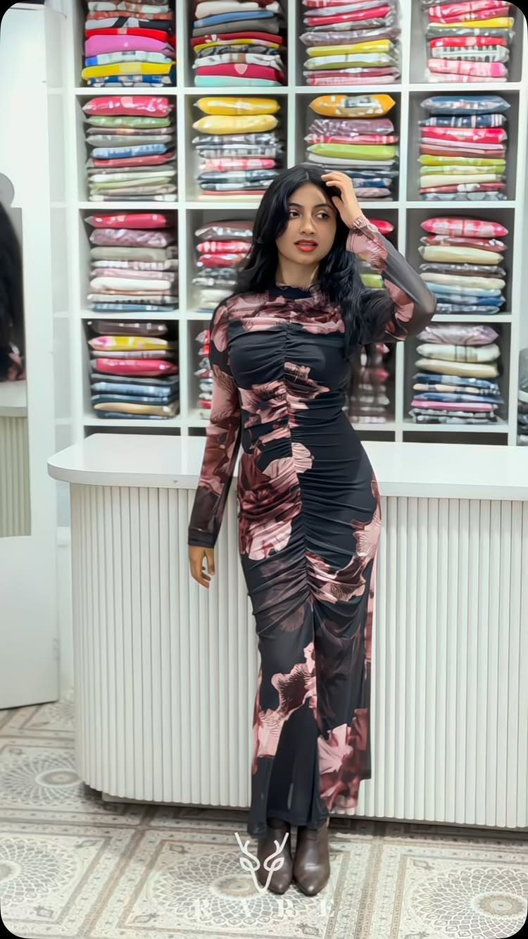 Woman posing in a long-sleeved, floral print bodycon dress inside a clothing boutique.