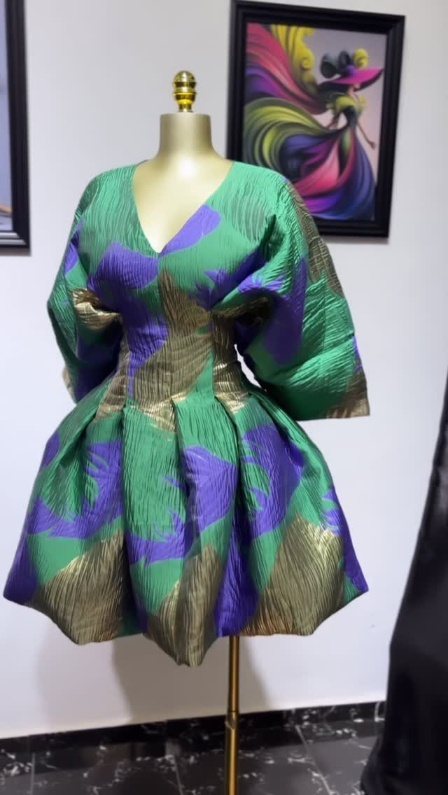 A short balloon silhouette dress with green, purple, and gold patterns on a mannequin.