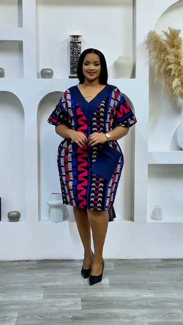 A woman posing in a patterned navy and pink short-sleeved shift dress.
