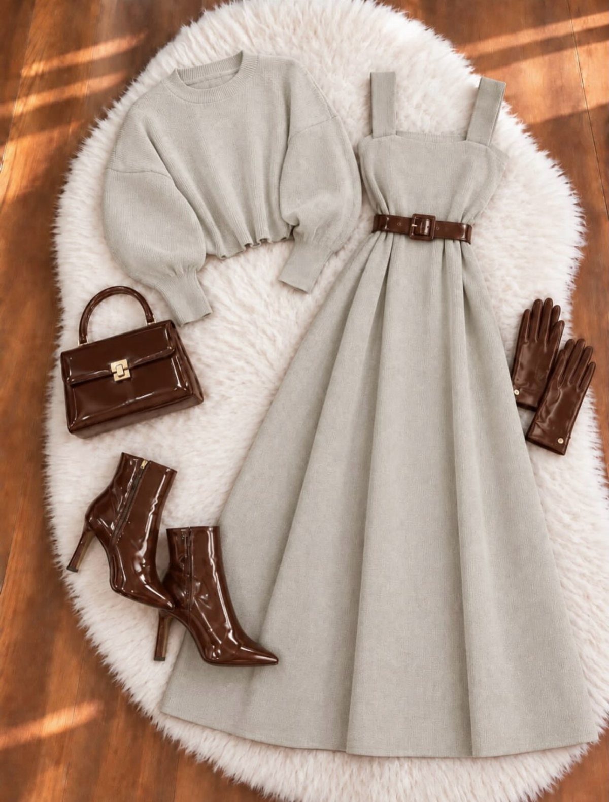 Grey knit sweater and matching sleeveless dress arranged with brown leather accessories on white fur.